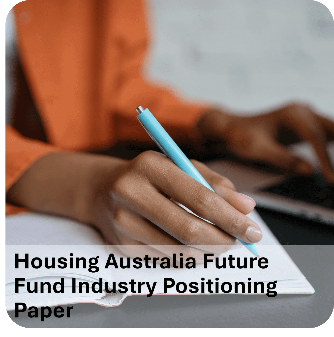 Person writing notes with a pen, laptop nearby, titled Housing Australia Future Fund Industry Positioning Paper.