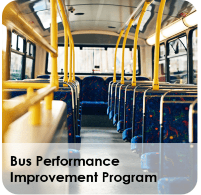 Empty city bus interior with blue seats and yellow handrails.