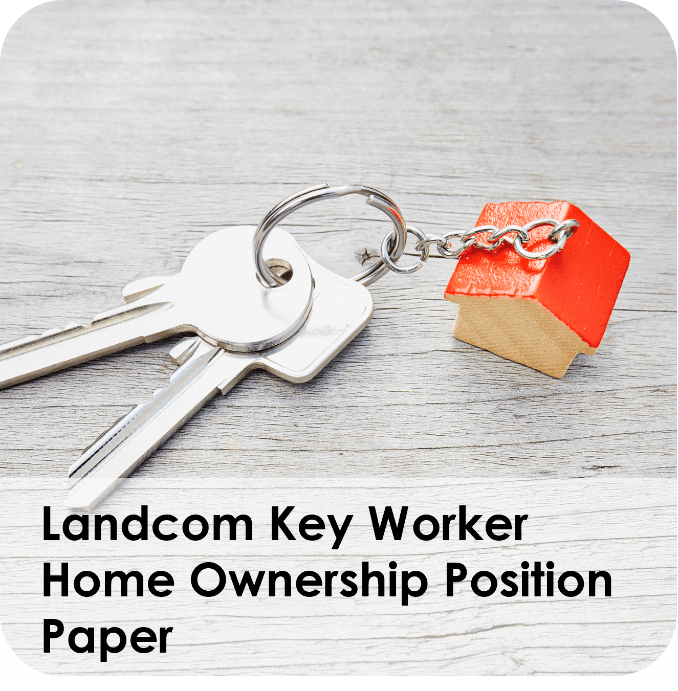 House-shaped keychain with silver keys on a wooden surface.