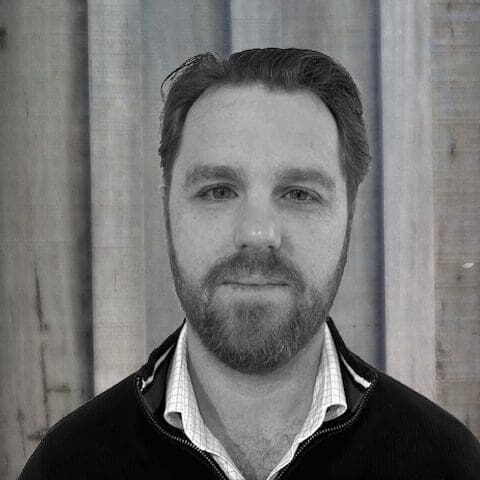 Black and white portrait of a man with a beard and collared shirt.