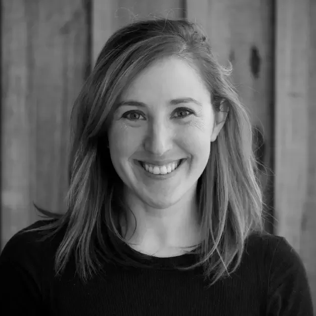 Portrait of a smiling woman with long hair against a wooden background.